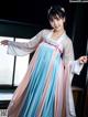 A woman in a blue and pink hanfu dress posing for a picture.