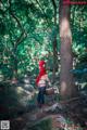 A woman dressed as a little red riding hood in the woods.