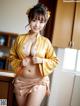 A woman in a yellow kimono posing in a kitchen.