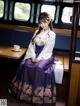 A woman in a purple and white hanbok sitting on a train.