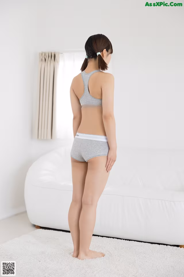 A woman standing in front of a white couch.