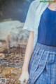 A woman in a blue shirt and plaid skirt standing in a stream.