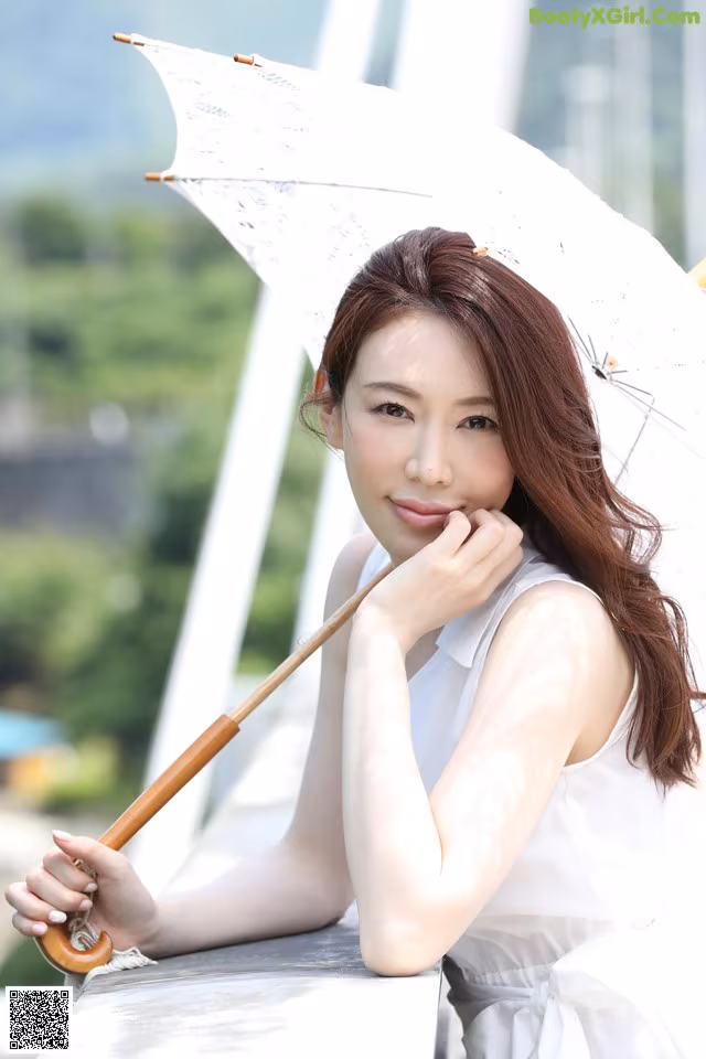 A woman in a white dress holding an umbrella.