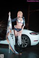 A woman in a bikini holding a flag next to a car.