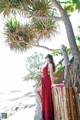 A woman in a red dress sitting on a wooden fence.