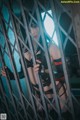 A woman in lingerie standing behind bars in a cage.