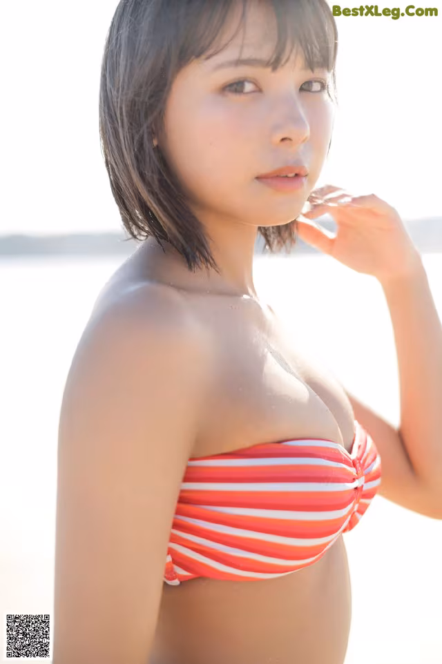 A woman in a red and white striped bikini on the beach.