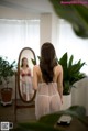 A woman standing in front of a mirror in a room.