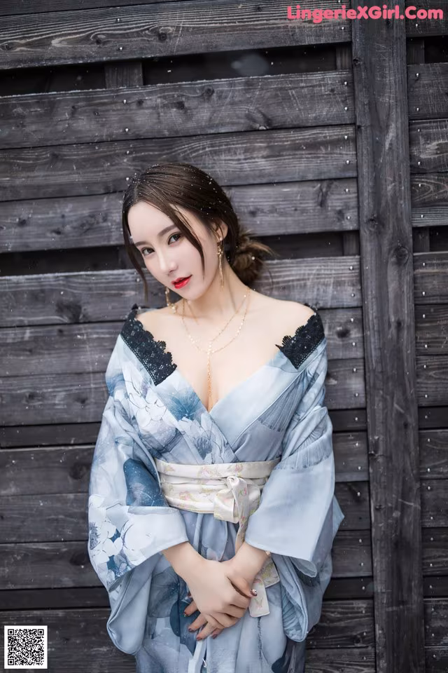 A woman in a blue kimono posing for a picture.