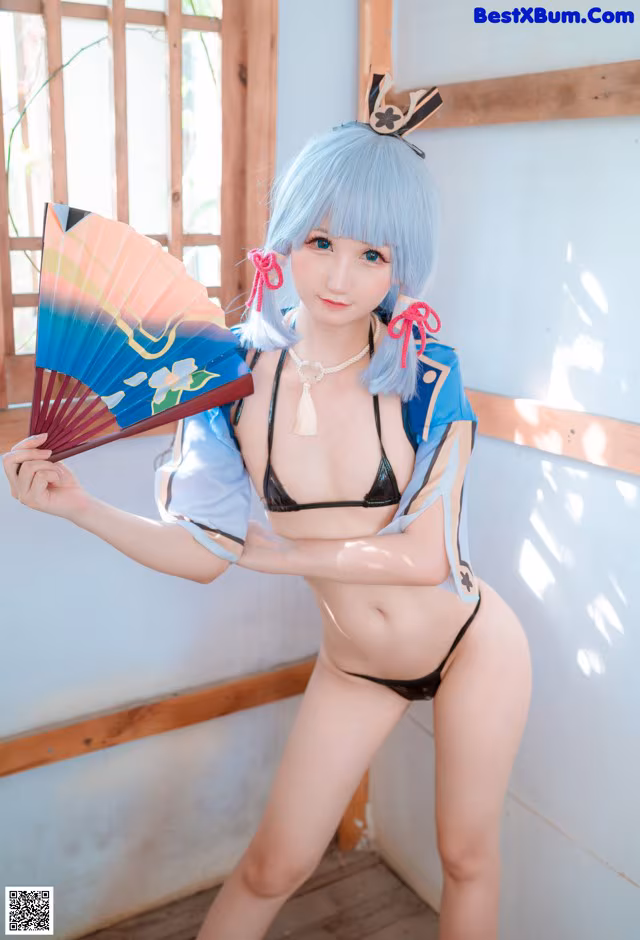 A woman in a bikini holding a fan.