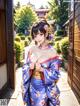 A woman in a blue kimono standing in front of a building.