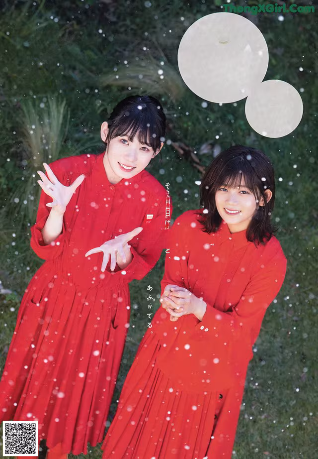 Two young women in red dresses standing in the snow.