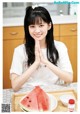 A woman sitting at a table with a plate of watermelon.