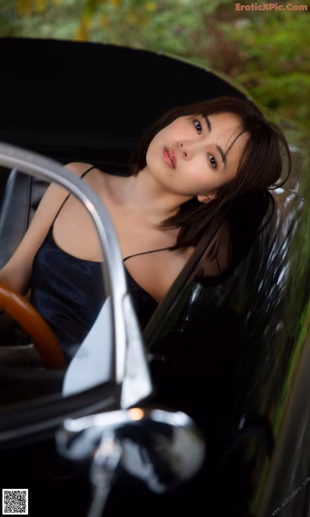 A woman sitting in the driver's seat of a vintage car.