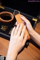 A woman's hand holding a brown leather bracelet.