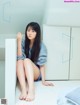 A woman sitting on the floor next to a white cabinet.