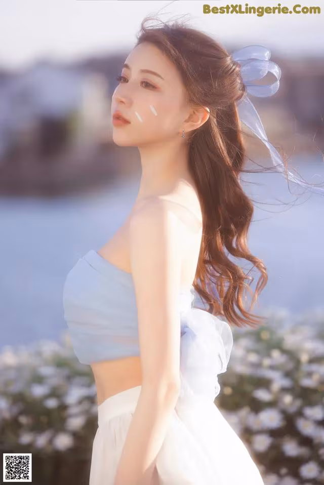 A woman in a white dress standing in front of a body of water.