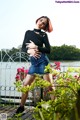 A woman in a black top and denim skirt posing for a picture.